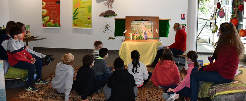 Les enfants assis par terre devant un petit théâtre en bois.