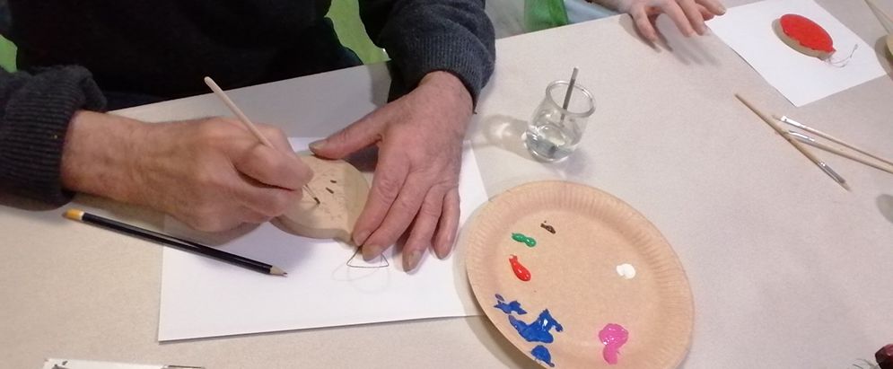 Les mais d'une perosnne agée avec le pinceau en train de décorer une boule de Noël.