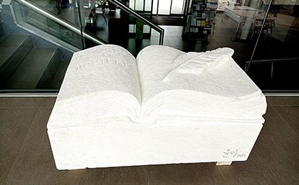 Sculpture en pierre : un livre ouvert avec une plume.