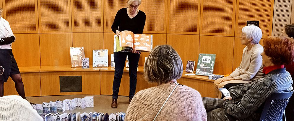 Une bibliothécaire montre un livre au public.